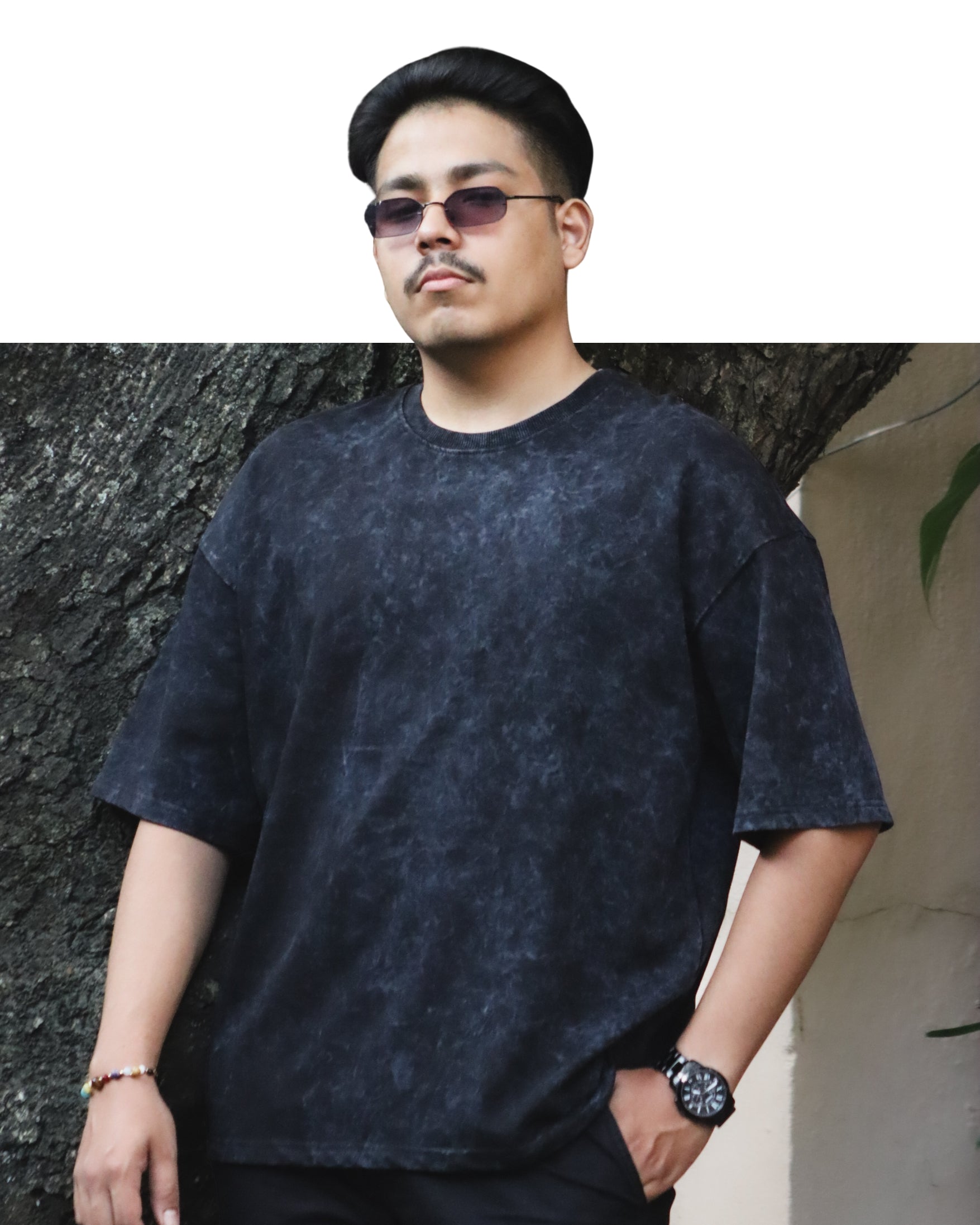 Man wearing a Acidwash t-shirt standing against a textured wall.