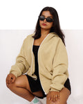 Woman wearing a beige hoodie and black shorts on a white background