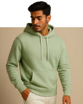 Man wearing a light green hoodie against a beige background
