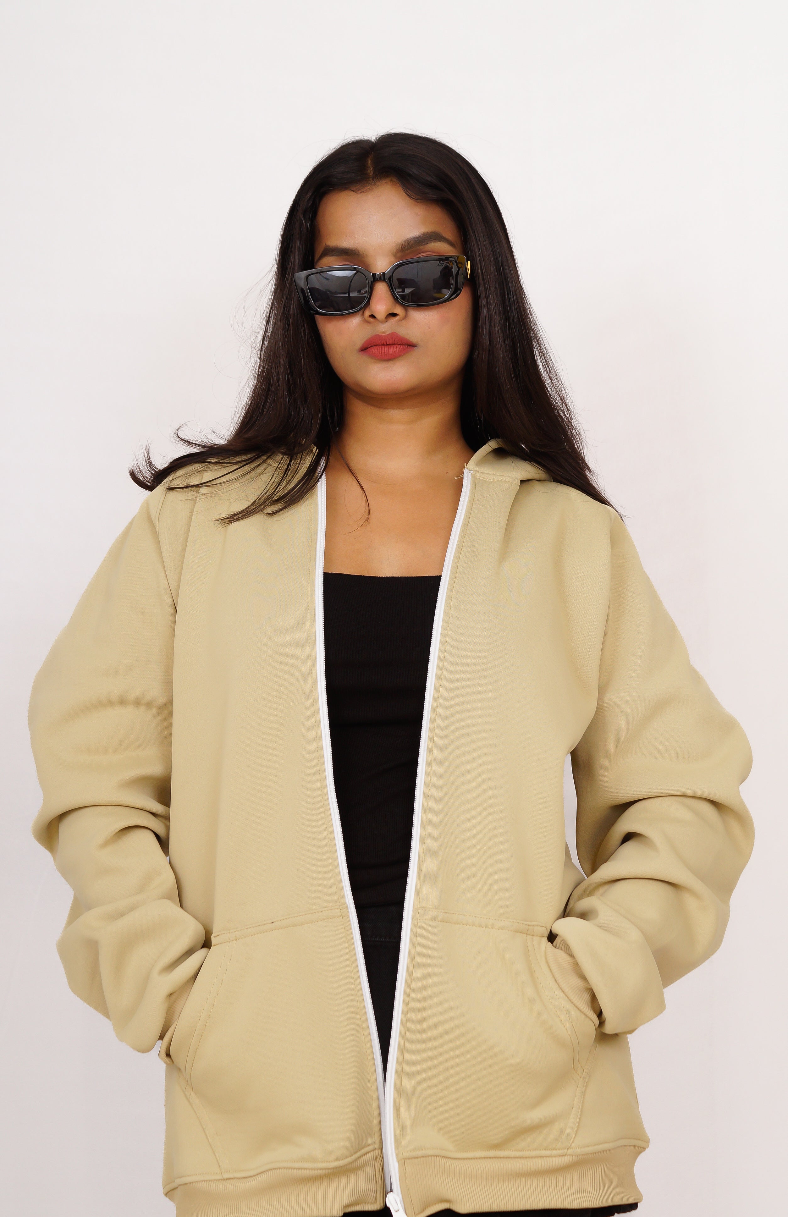 Woman wearing a beige hoodie and sunglasses on a white background