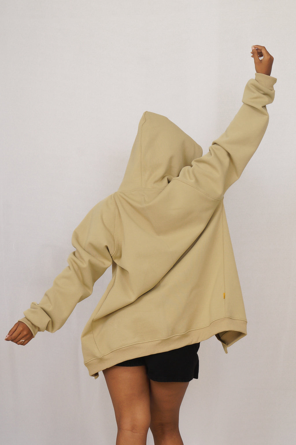 Person wearing a beige hoodie with a plain background