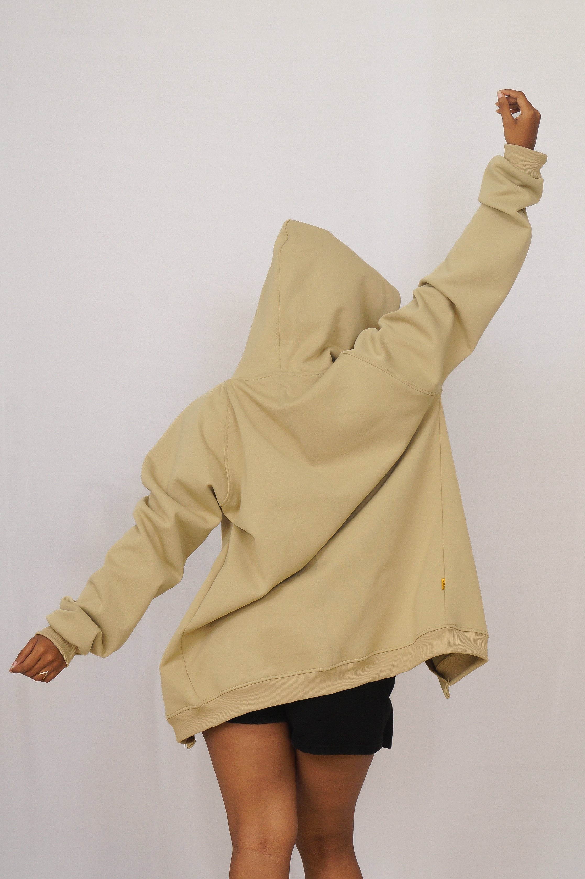 Person wearing a beige hoodie with a plain background