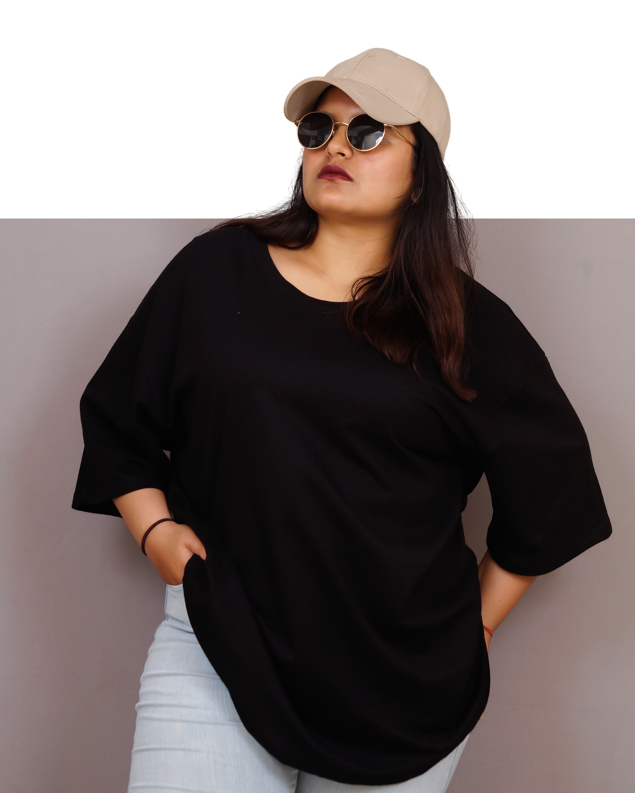 Person wearing a black top, beige cap, and sunglasses against a plain background