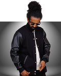 Person wearing a black varsity jacket with a white shirt underneath on a gray background