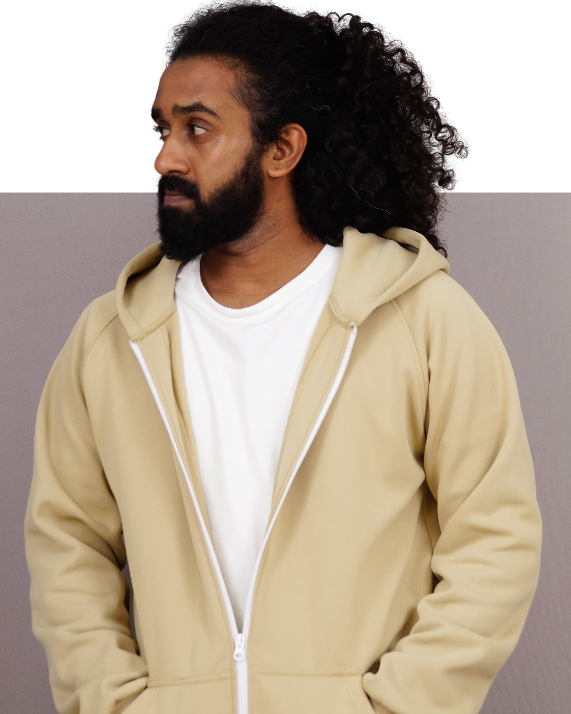 Man wearing a beige hoodie with a plain background