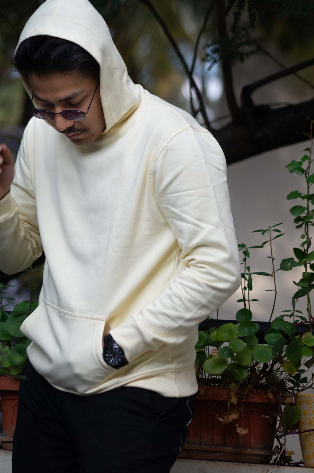 Person wearing a white hoodie in an indoor setting with plants