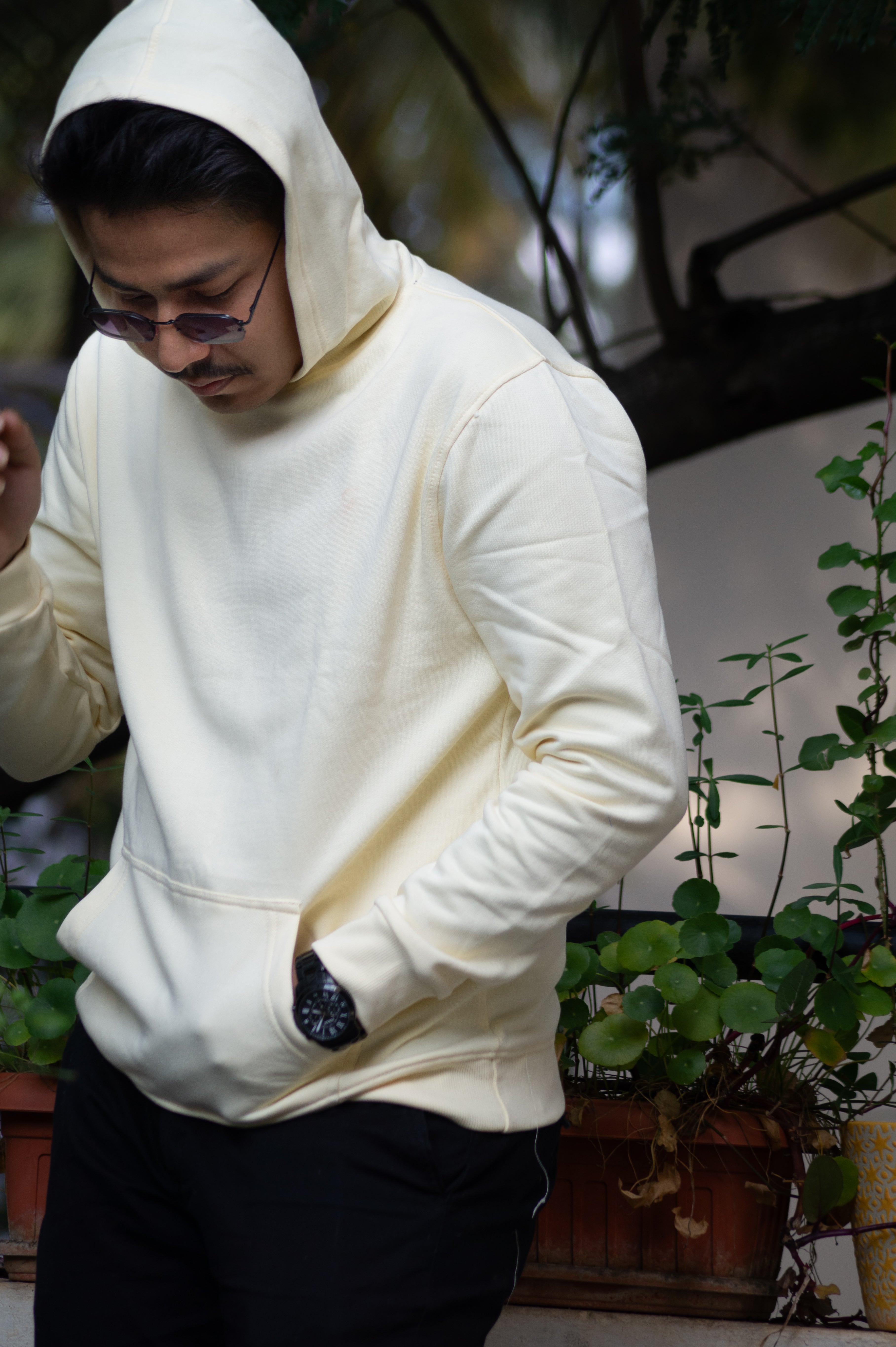 Person wearing a white hoodie in an indoor setting with plants