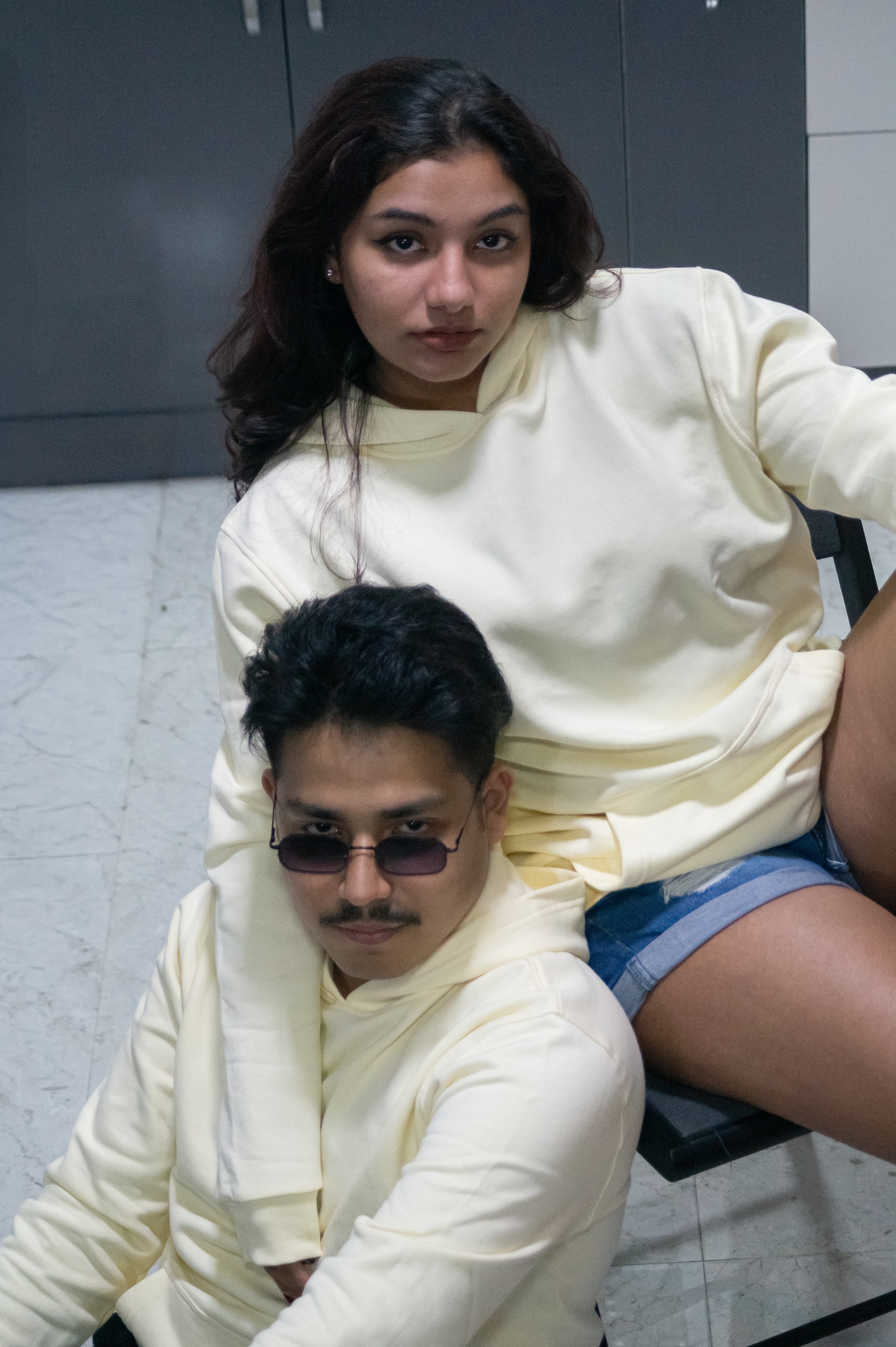 Two people sitting together in a casual setting with a neutral background