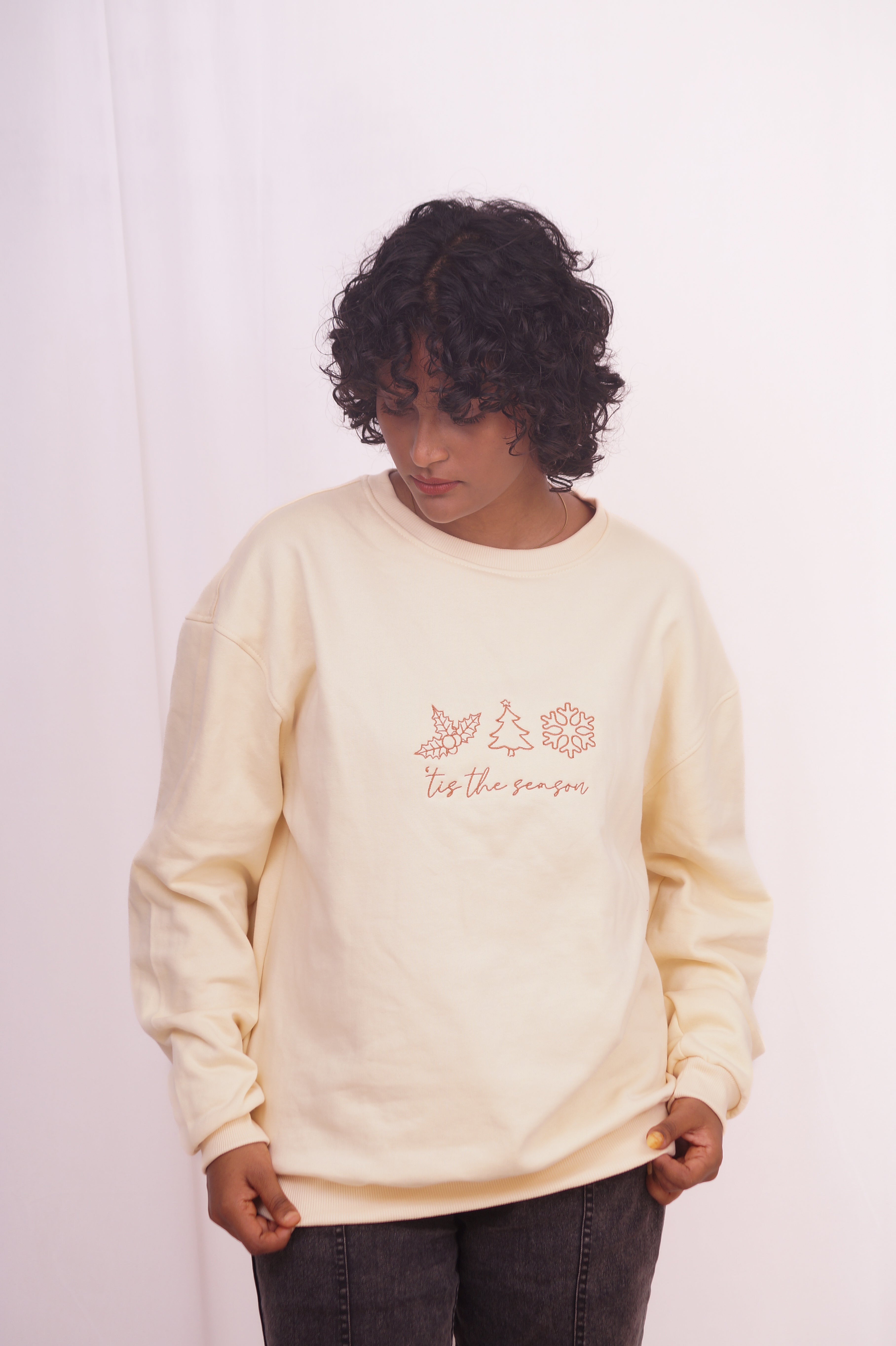 Person wearing a light-colored sweatshirt with text and graphics on a plain background