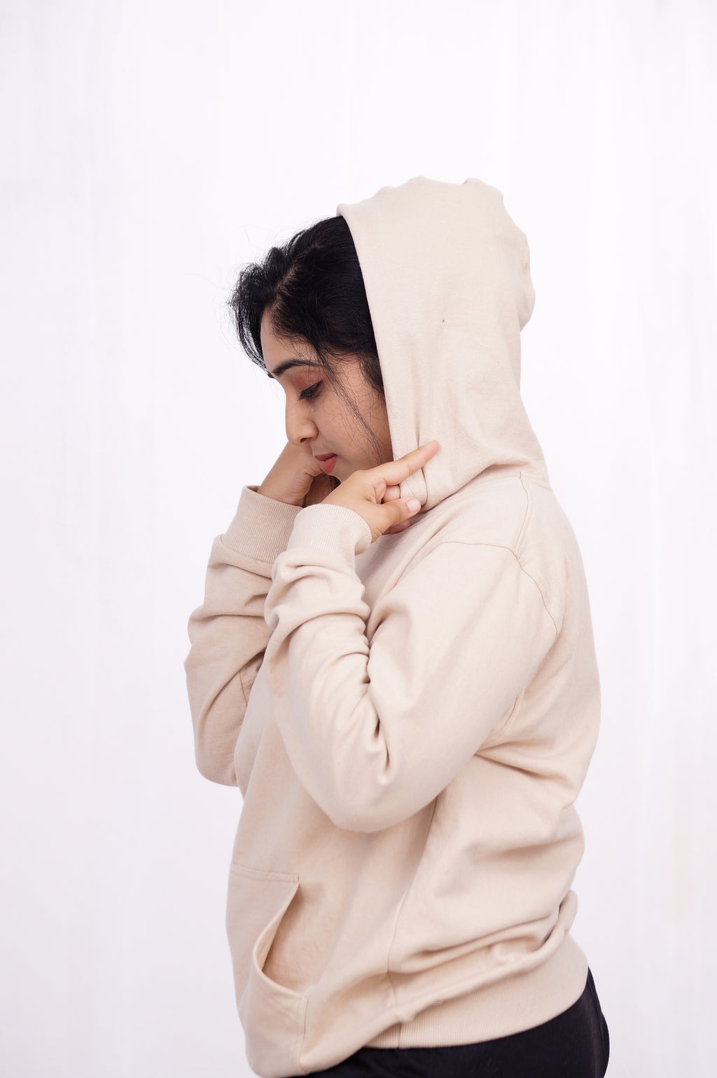Person wearing a beige hoodie on a white background