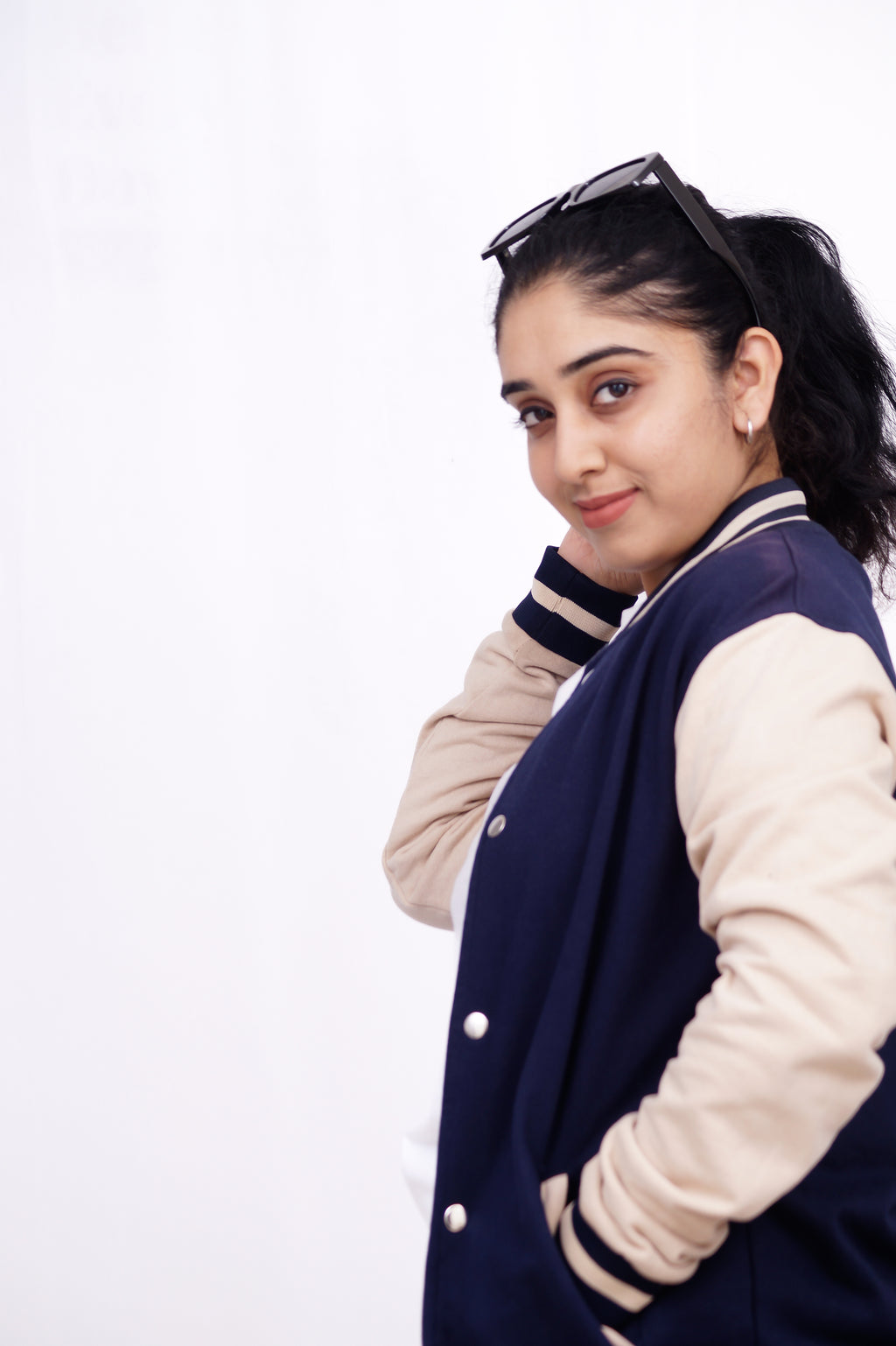 Person wearing a navy blue and beige varsity jacket on a white background