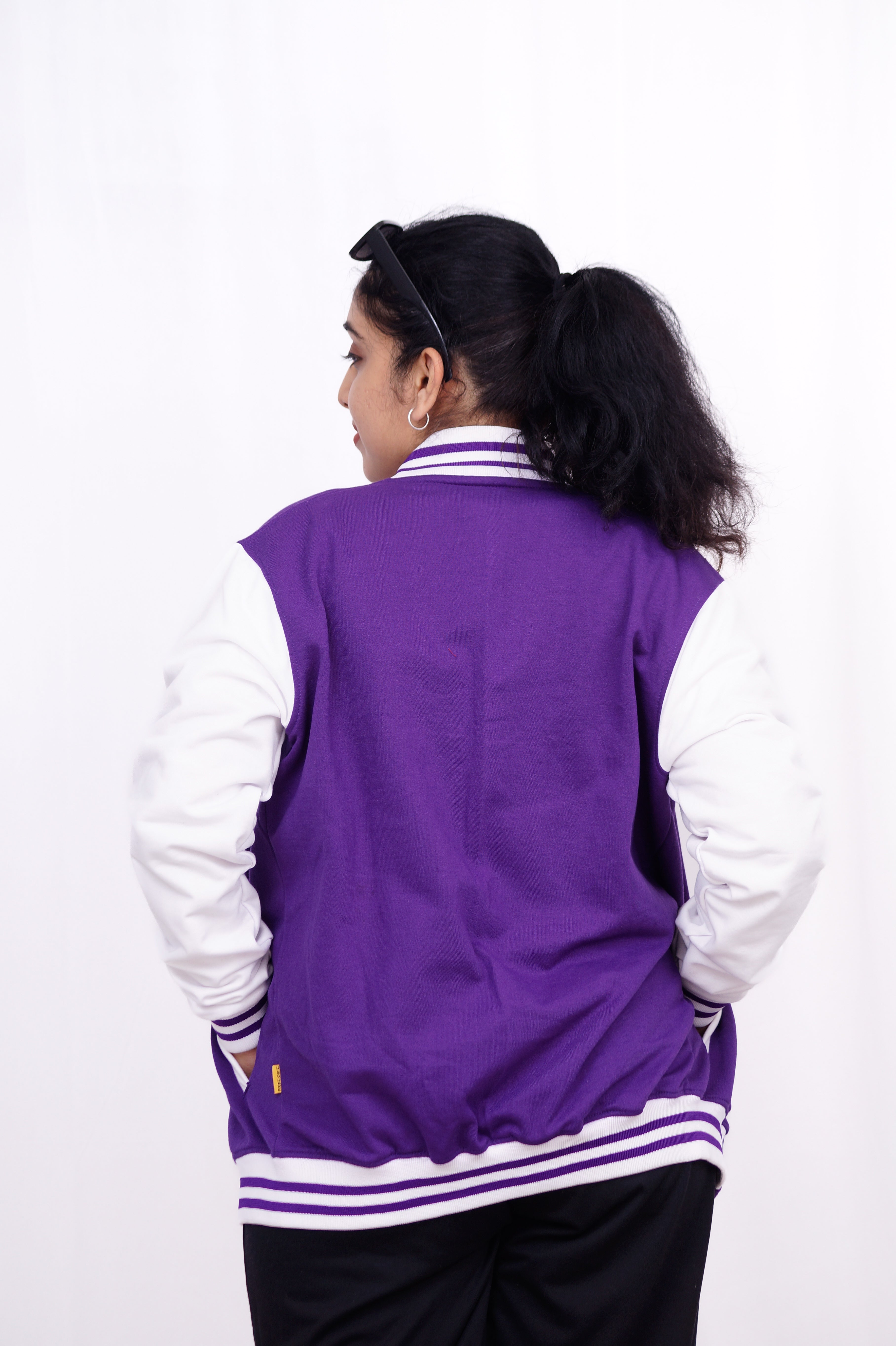 Person wearing a purple and white varsity jacket on a white background