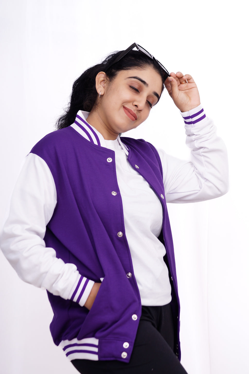 Woman wearing a purple and white varsity jacket on a white background