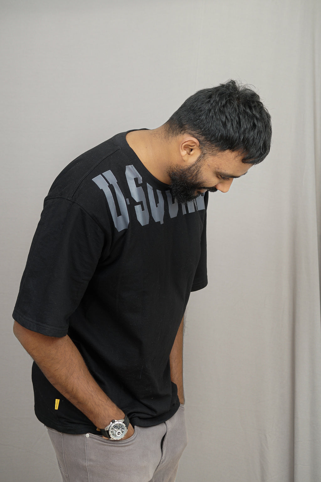 Man wearing a black t-shirt with text, standing against a plain background