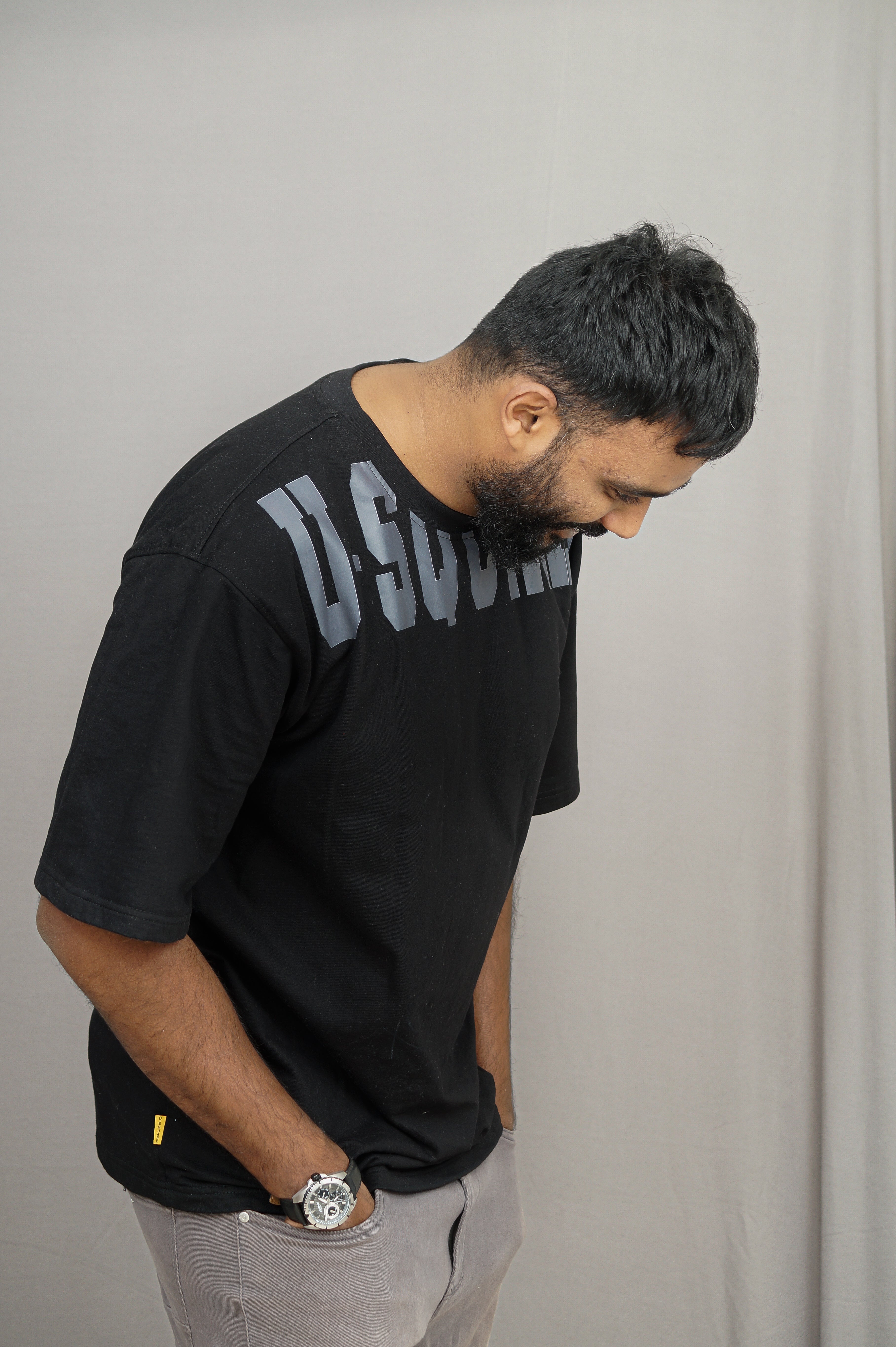 Man wearing a black t-shirt with text, standing against a plain background