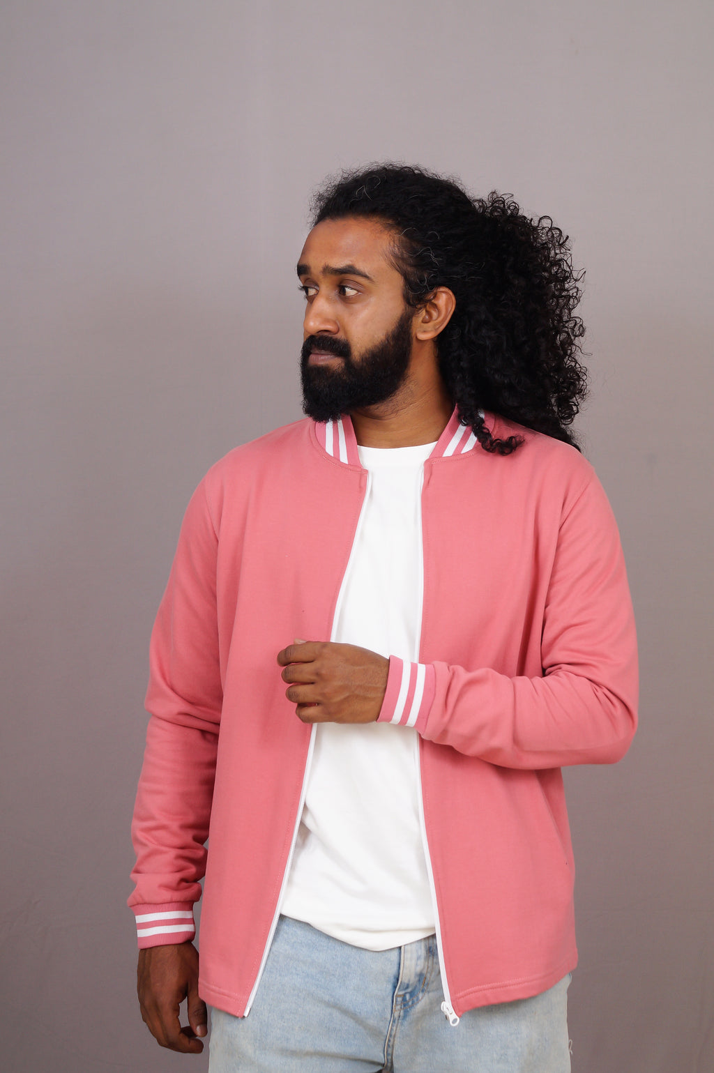 Man wearing a pink jacket with white stripes on a plain background