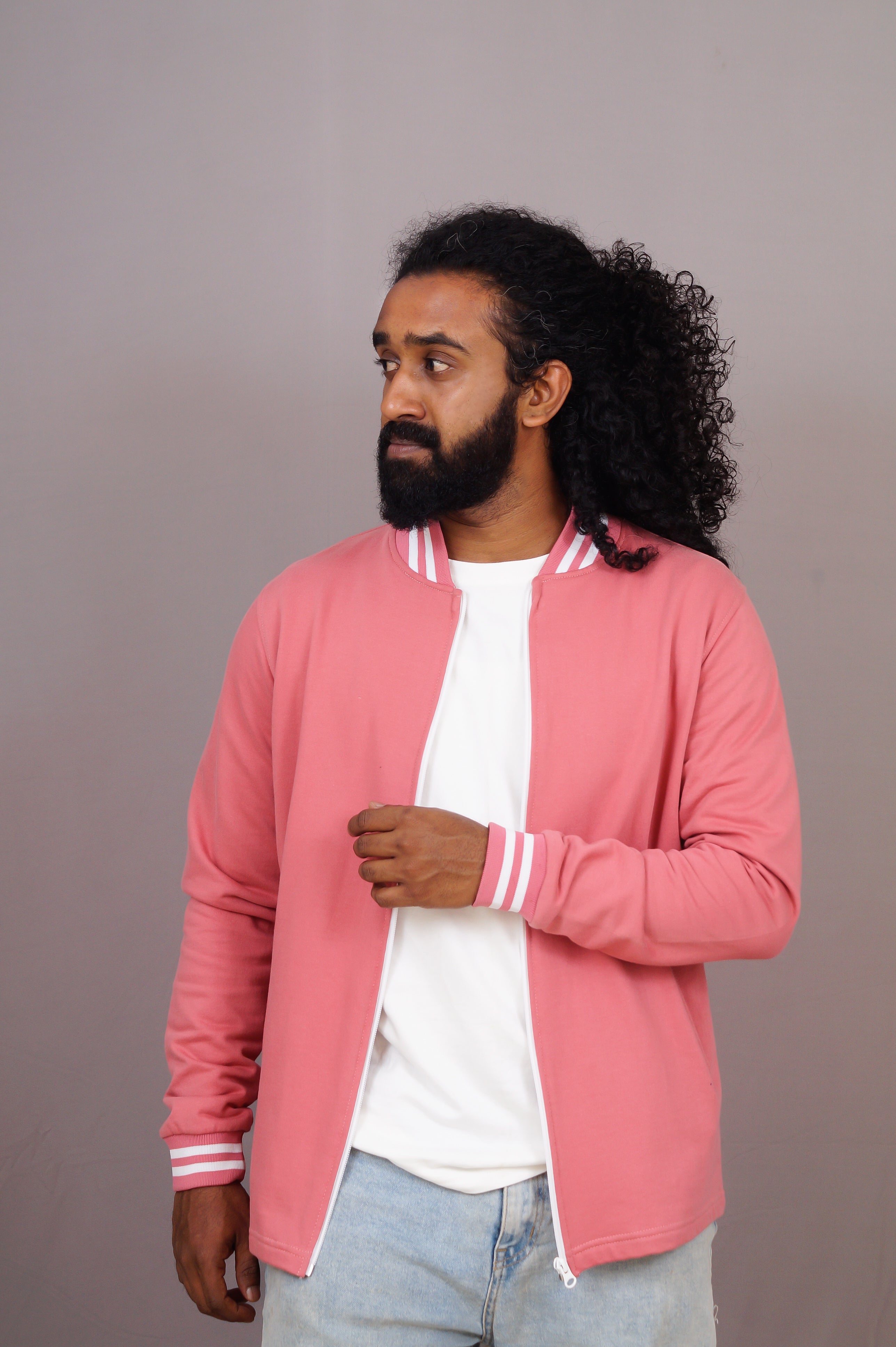 Man wearing a pink jacket with white stripes on a plain background