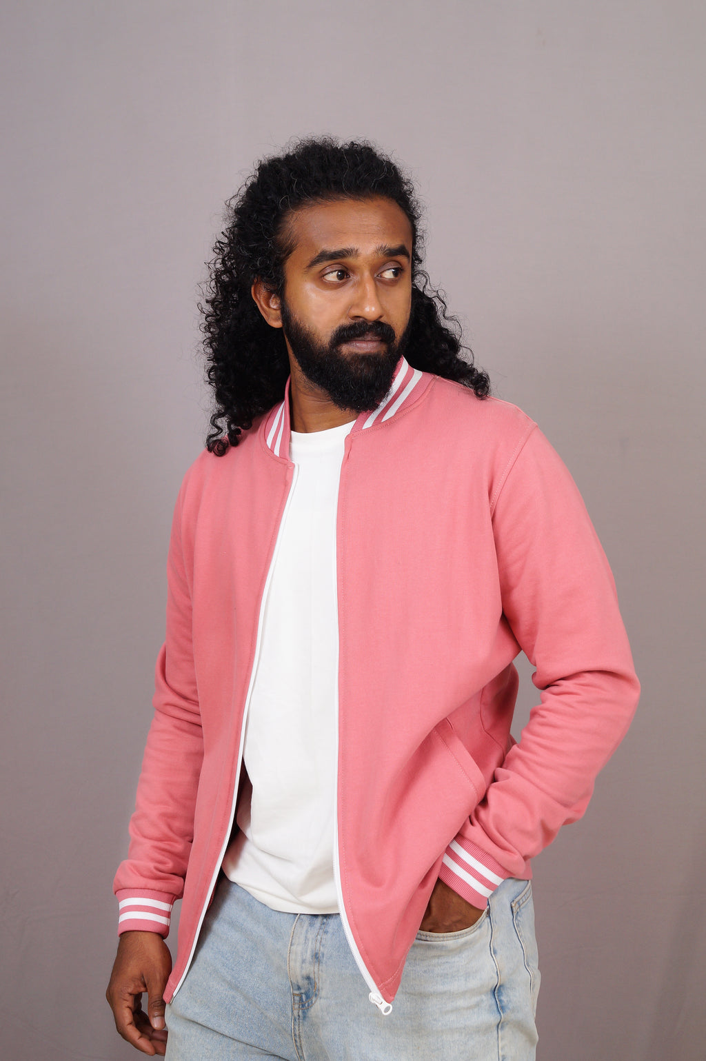 Man wearing a pink jacket with white stripes on a plain background