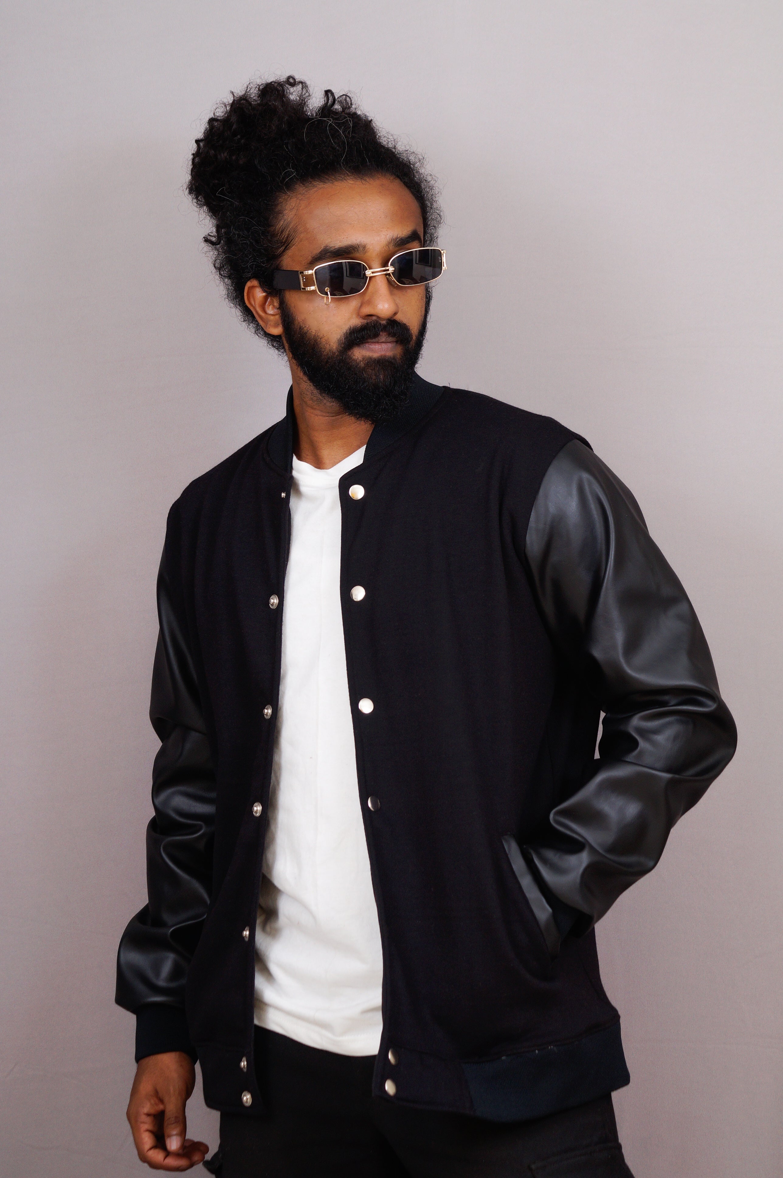 Man wearing a black leather jacket over a white shirt against a plain background