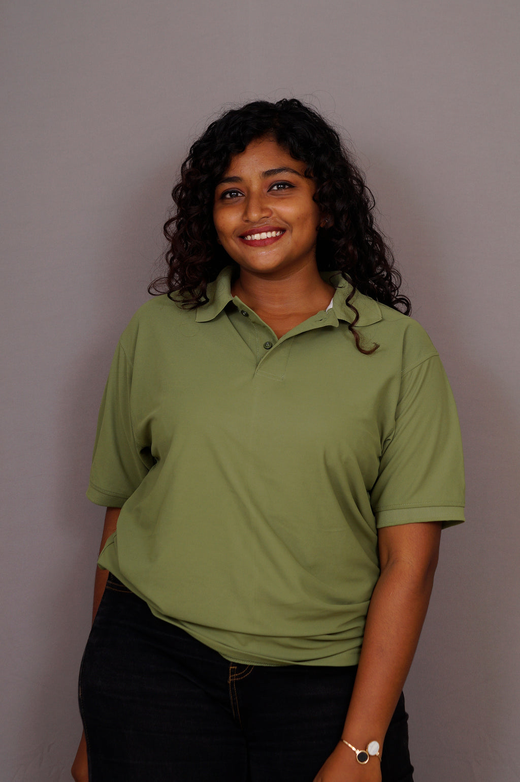 Woman wearing a green polo shirt against a gray background