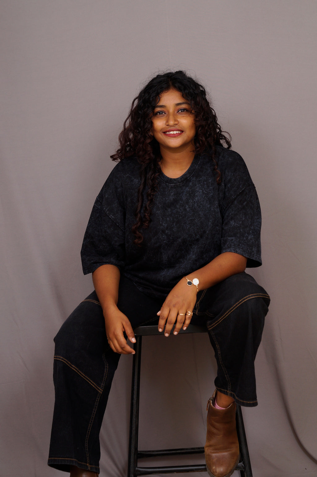 Woman sitting on a chair against a plain background