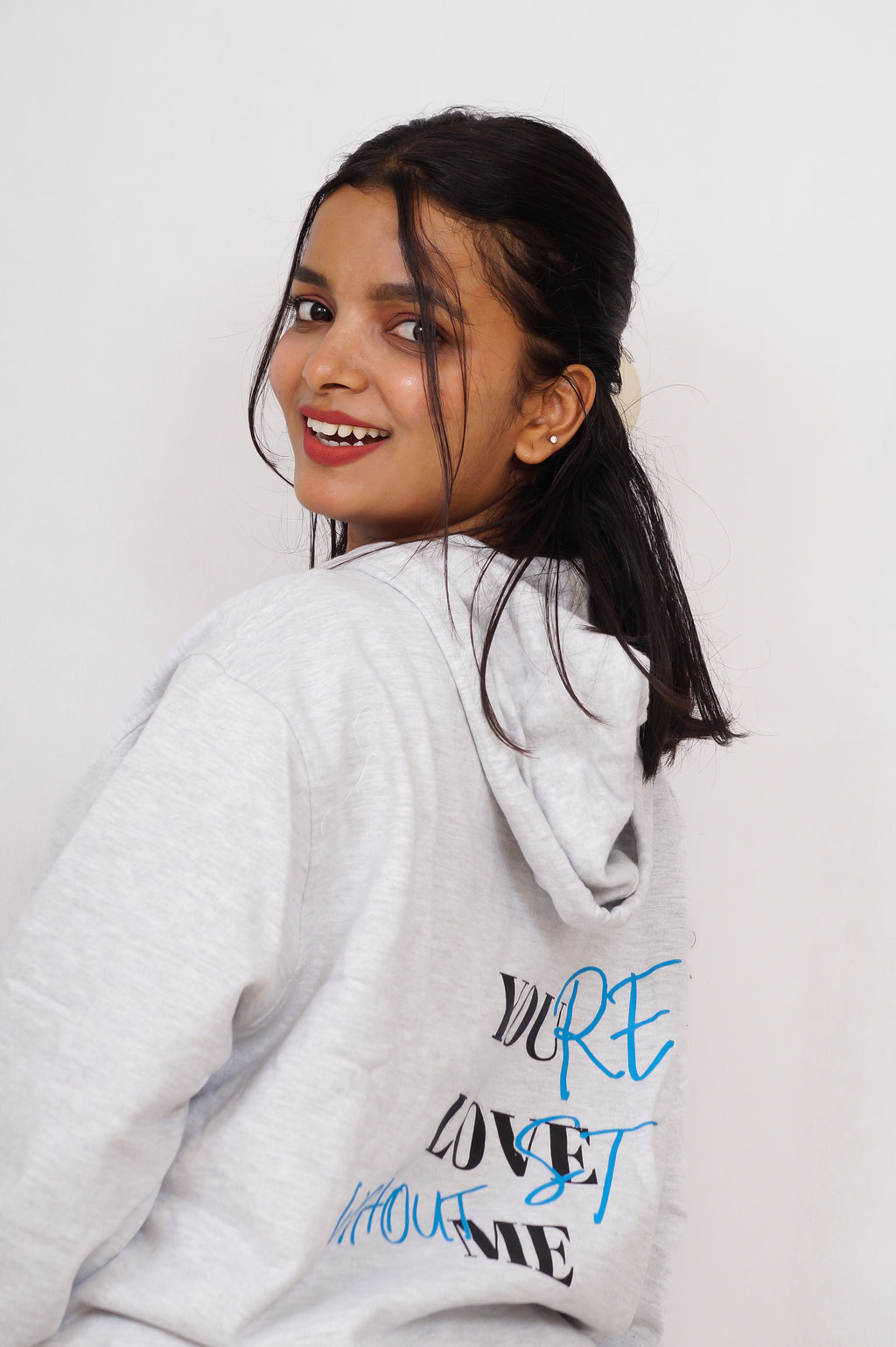Person wearing a white hoodie with text on a plain background