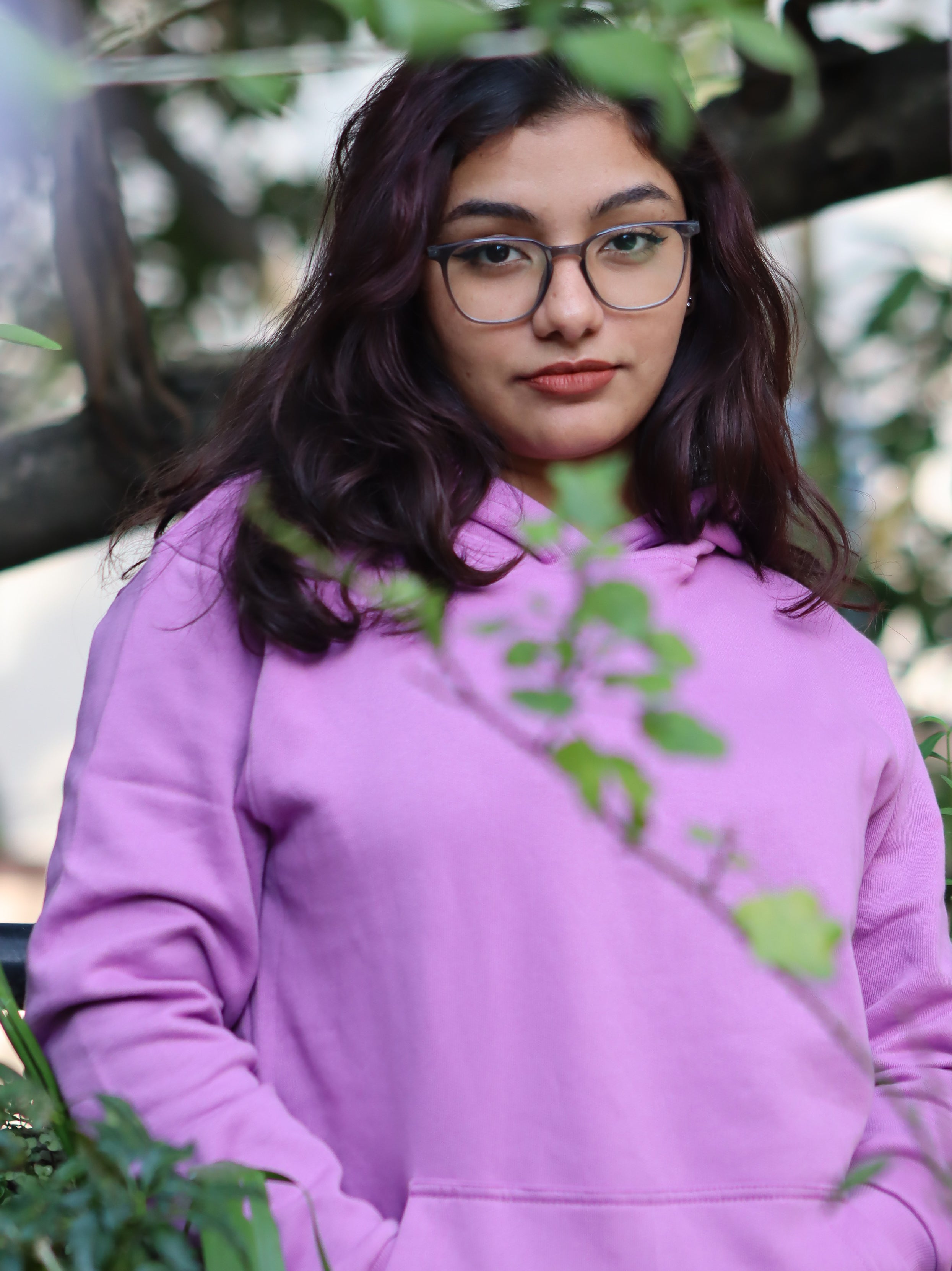 Person wearing a purple hoodie with green leaves in the foreground