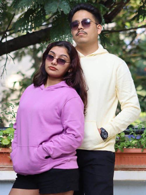 Two people wearing sunglasses outdoors with greenery in the background