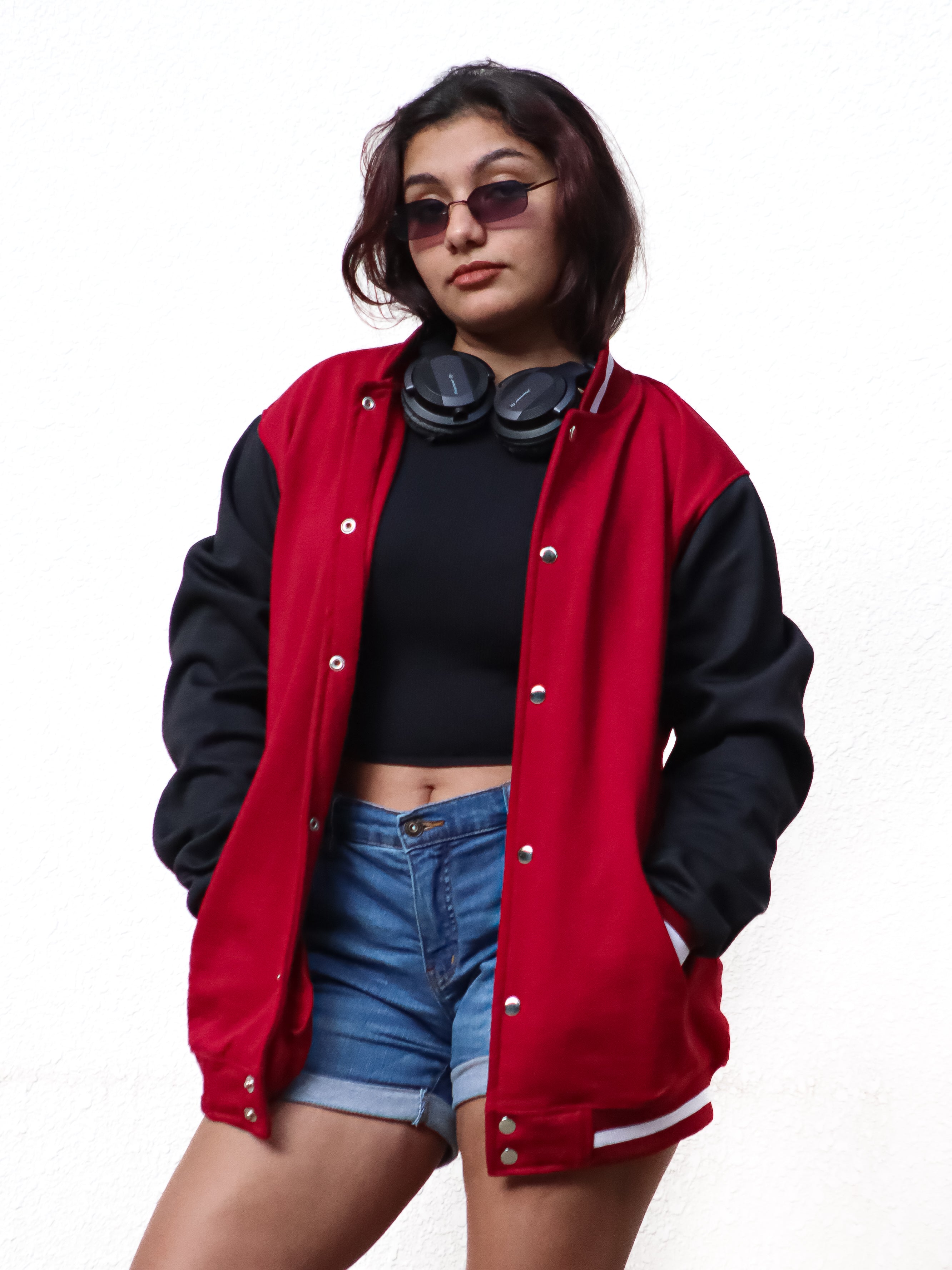Person wearing a red and black varsity jacket with a white background