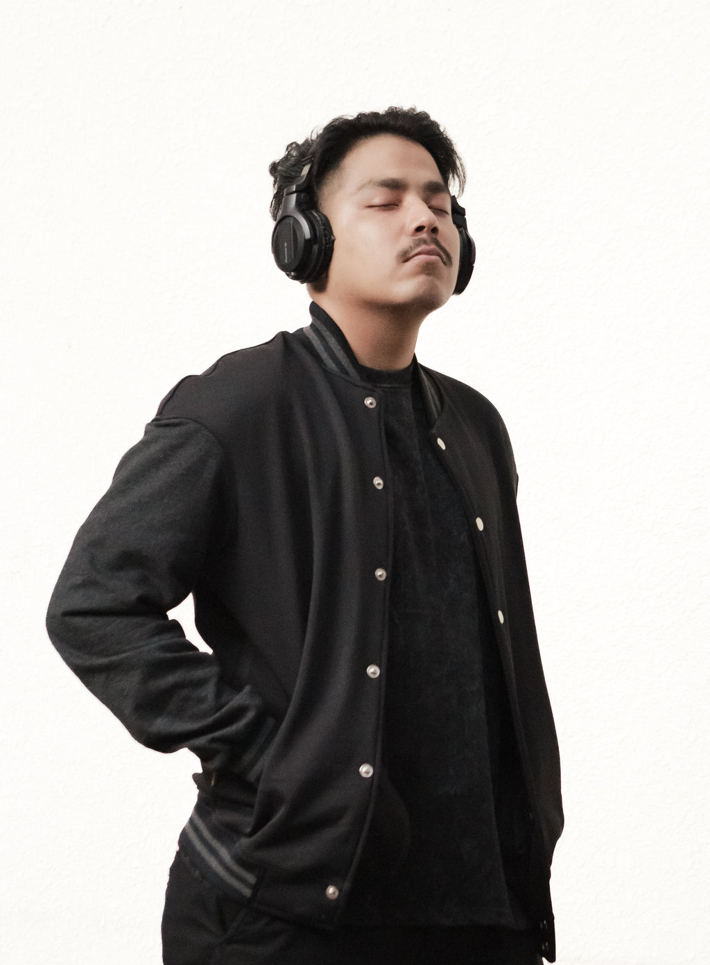 Man wearing a black jacket and headphones on a white background