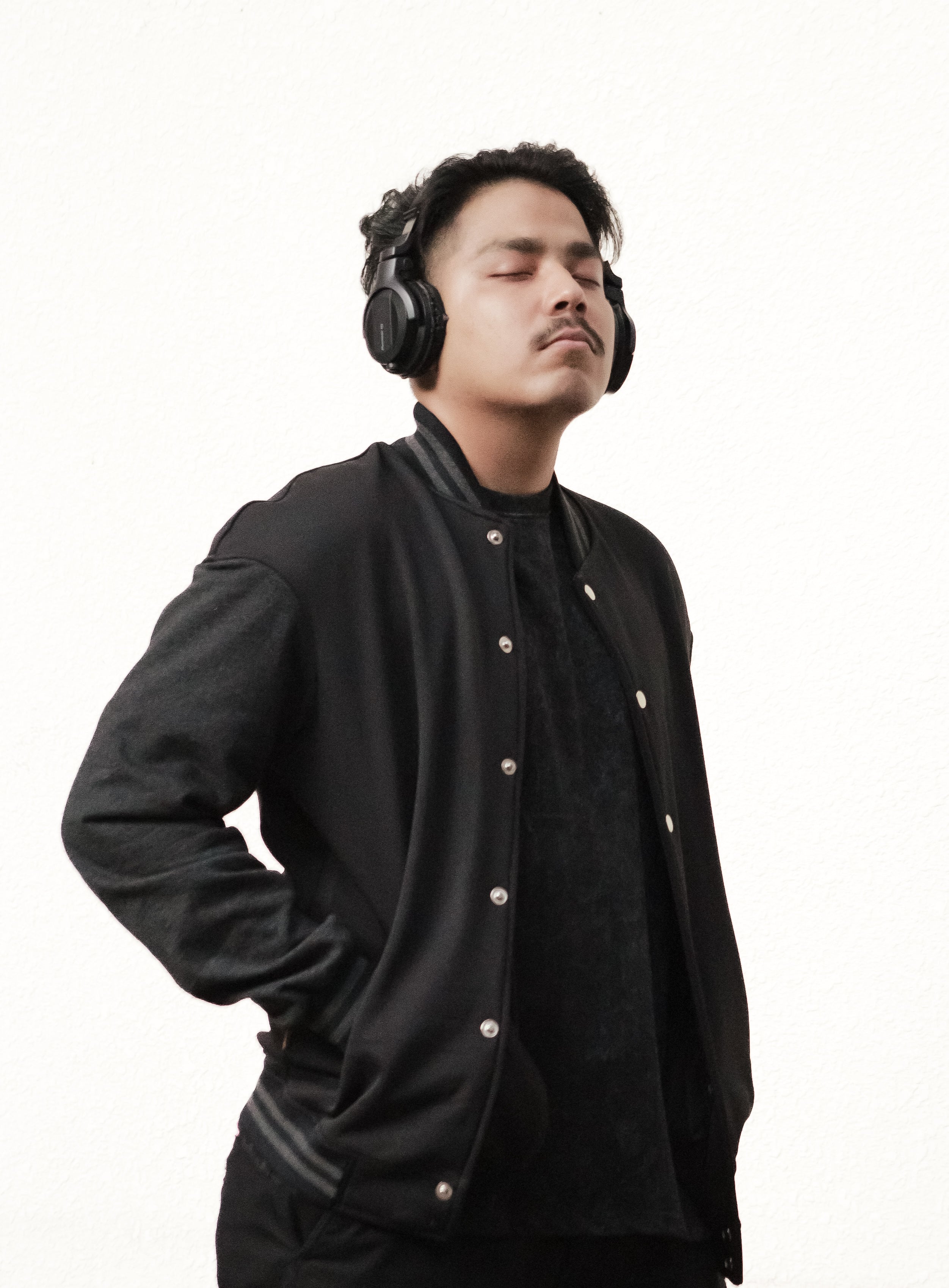 Man wearing a black jacket and headphones on a white background
