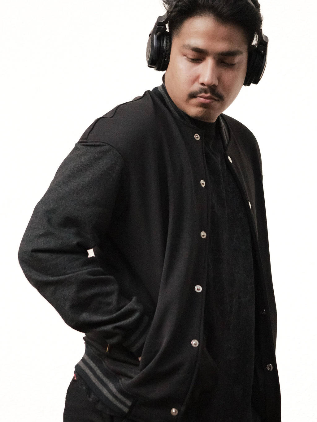 Man wearing a black jacket and headphones on a white background