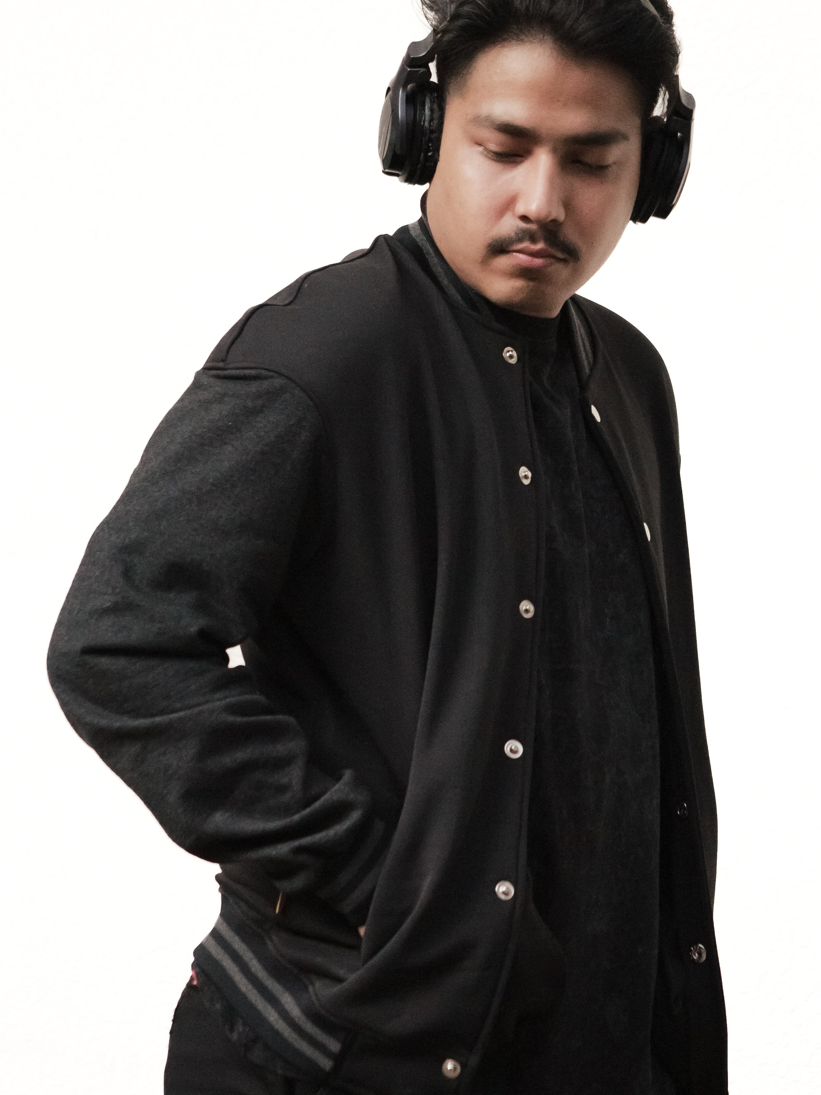 Man wearing a black jacket and headphones on a white background