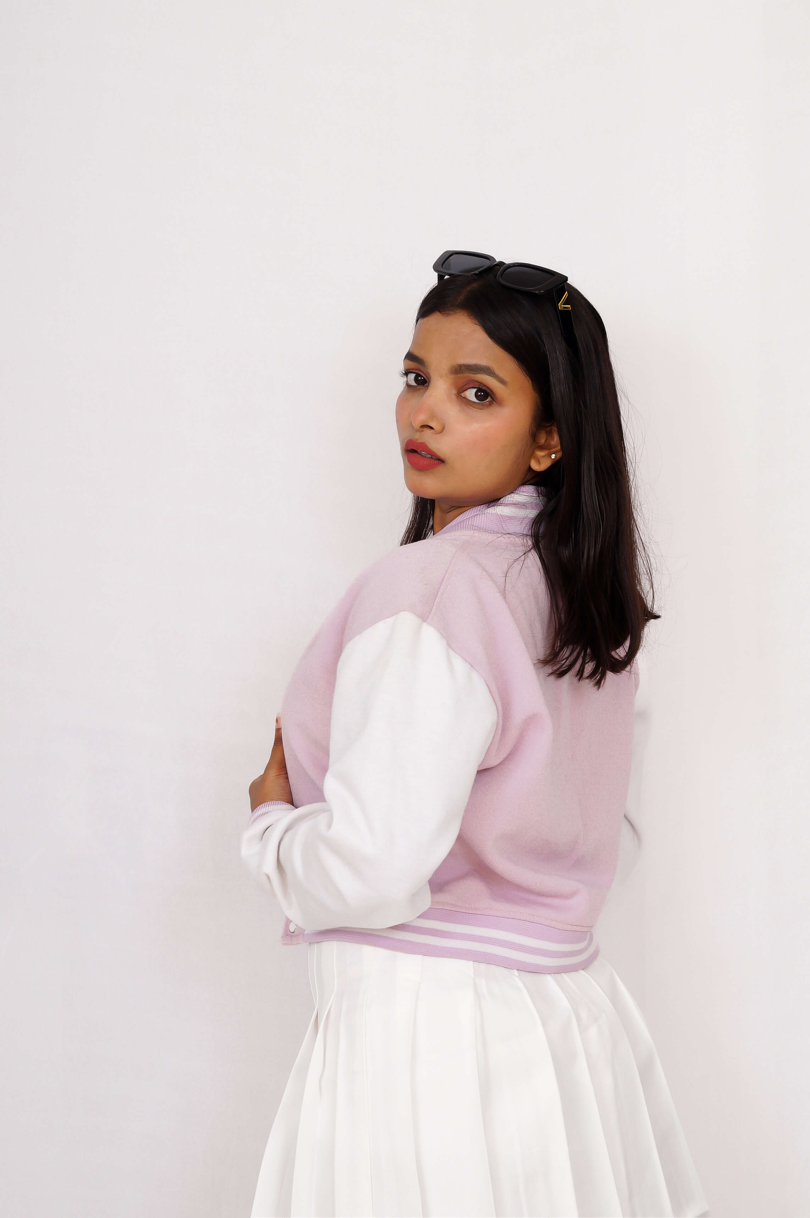 Woman wearing a light lavender sweater over a white shirt with a white background