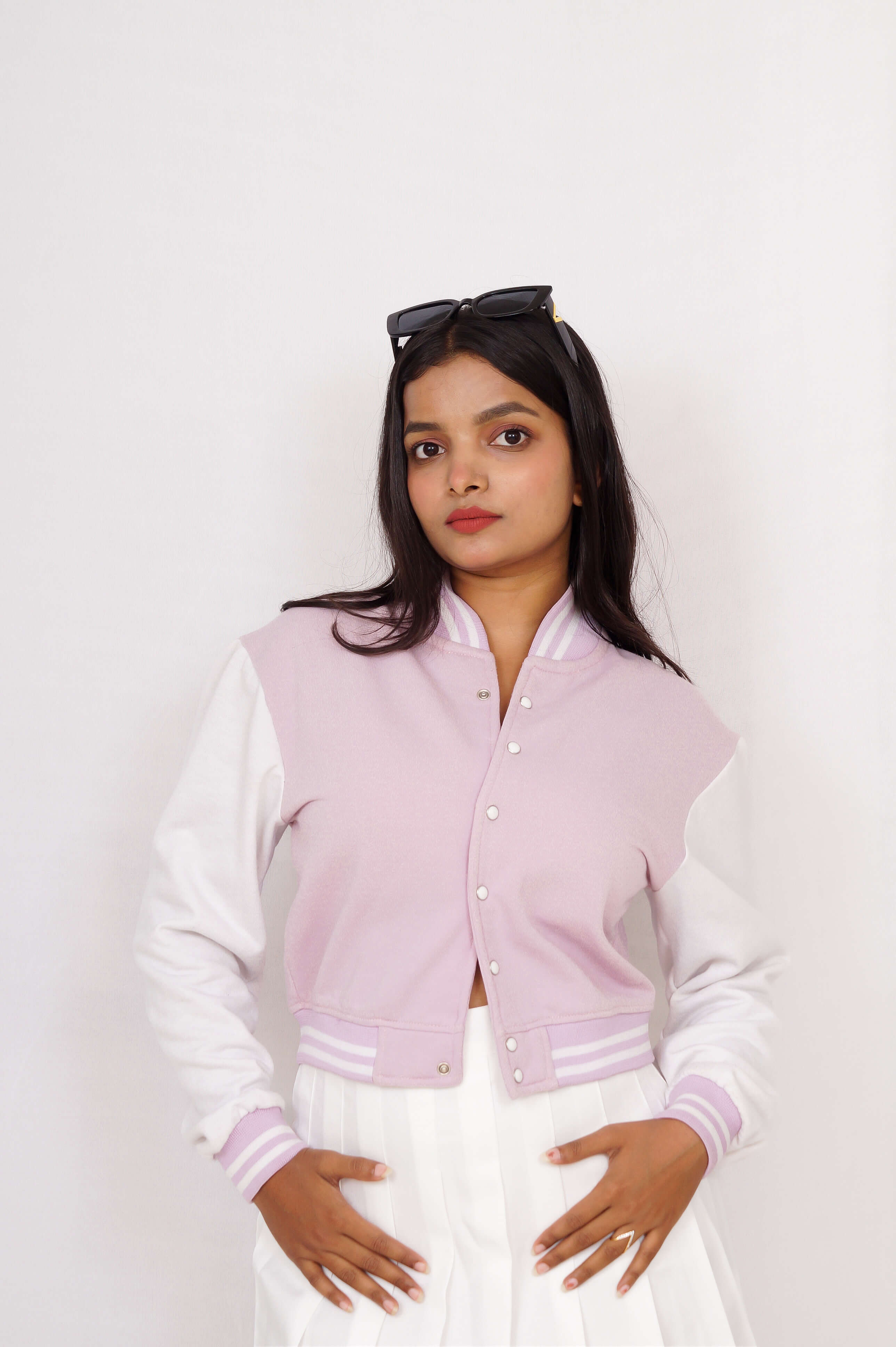 Woman wearing a light purple and white varsity jacket on a plain background