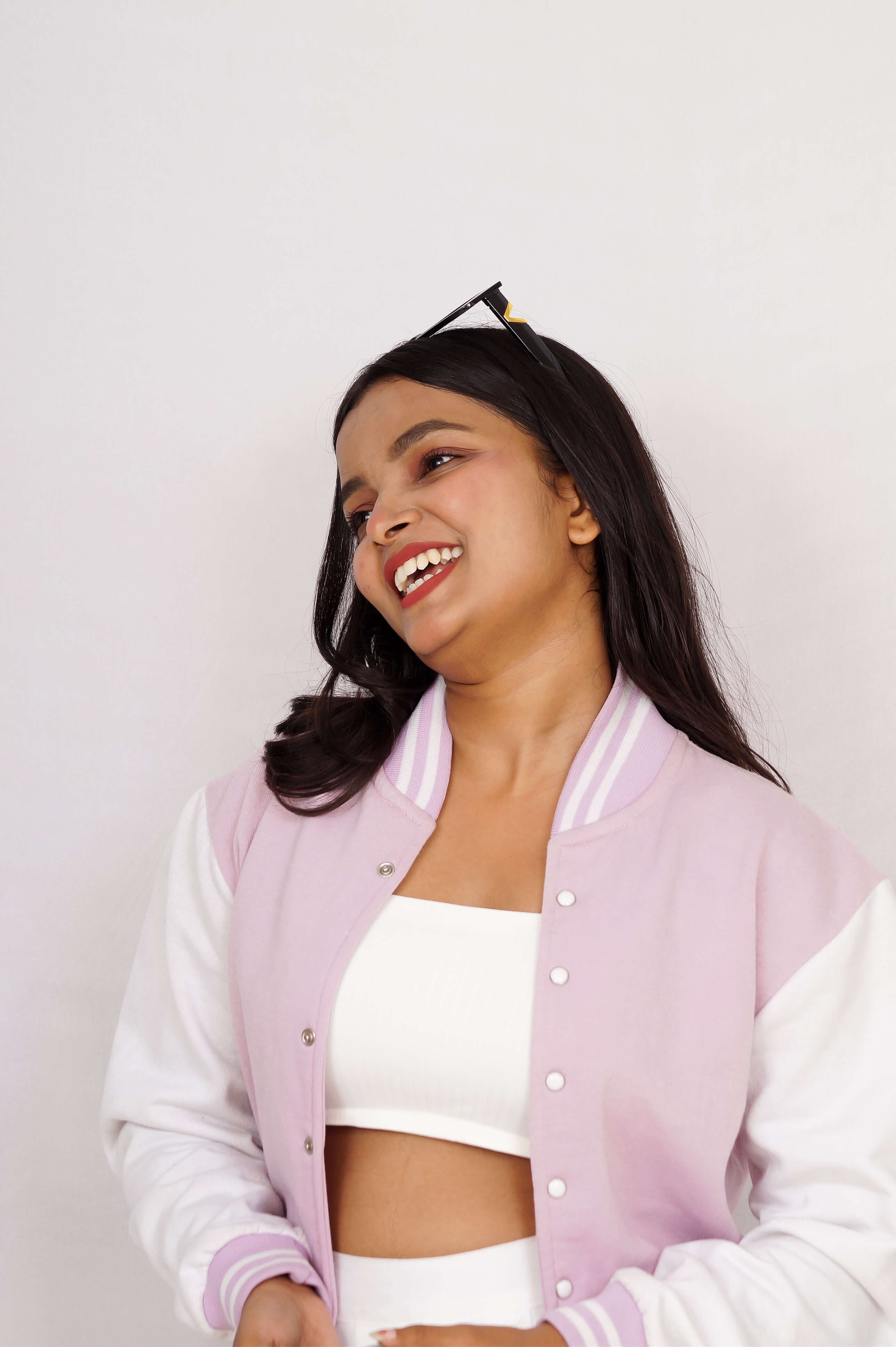 Woman wearing a light purple varsity jacket over a white top against a plain background