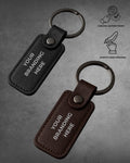 Two leather keychains with customizable text on a gray background