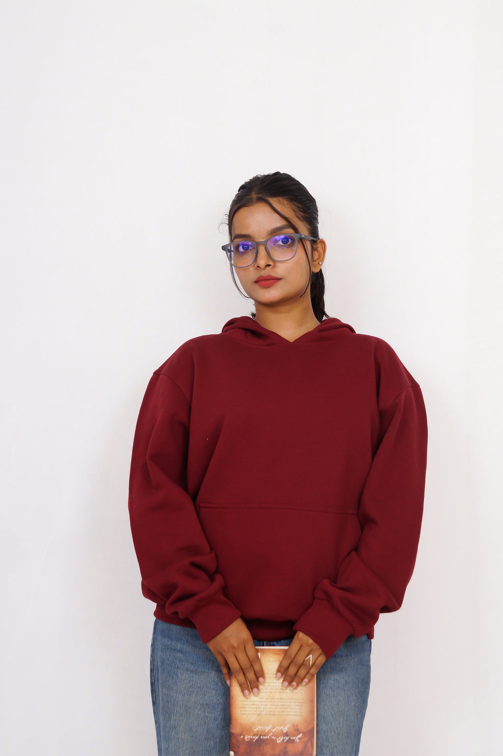 Person wearing a maroon hoodie and blue jeans against a white background