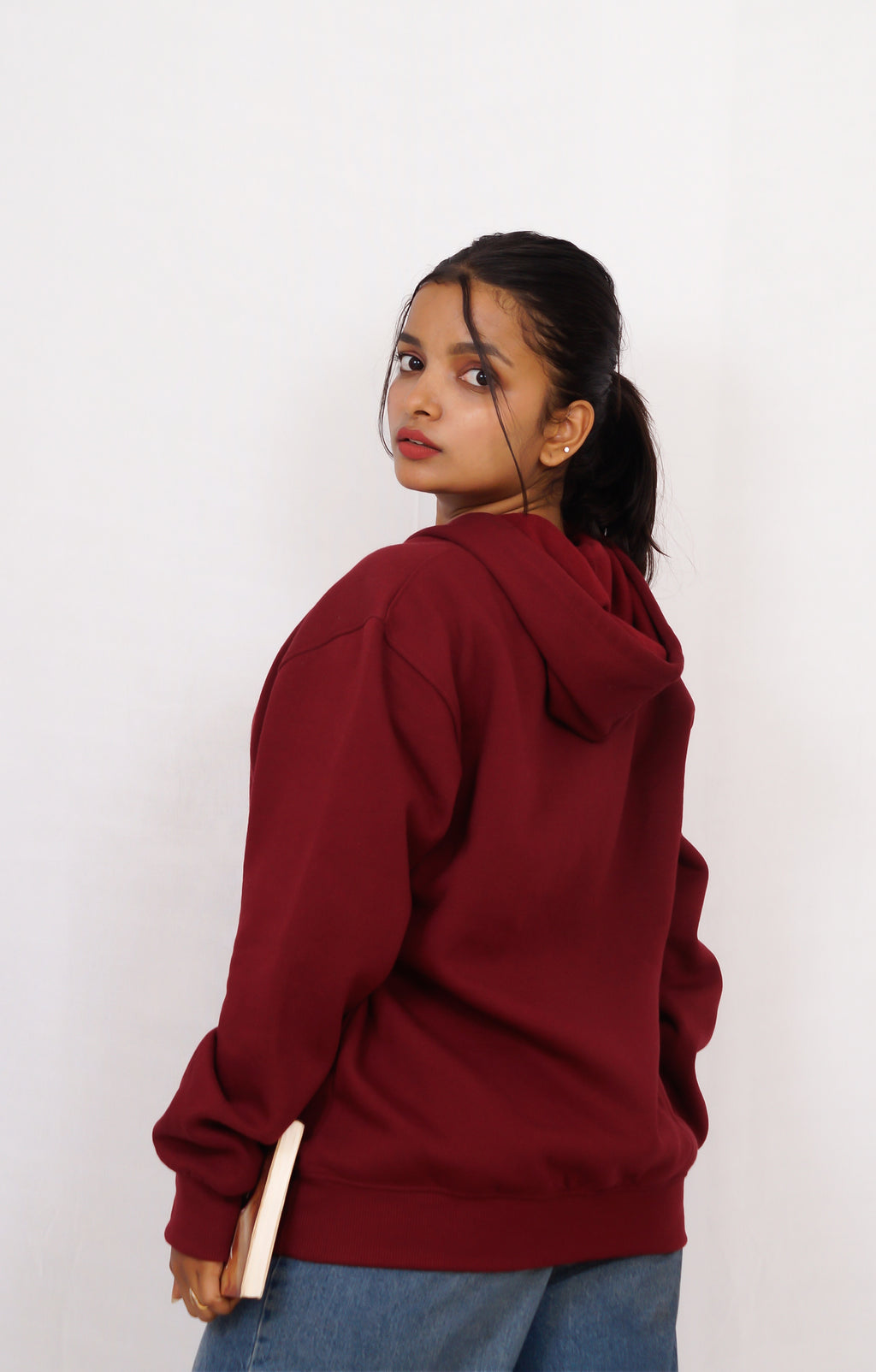 Person wearing a maroon hoodie against a white background