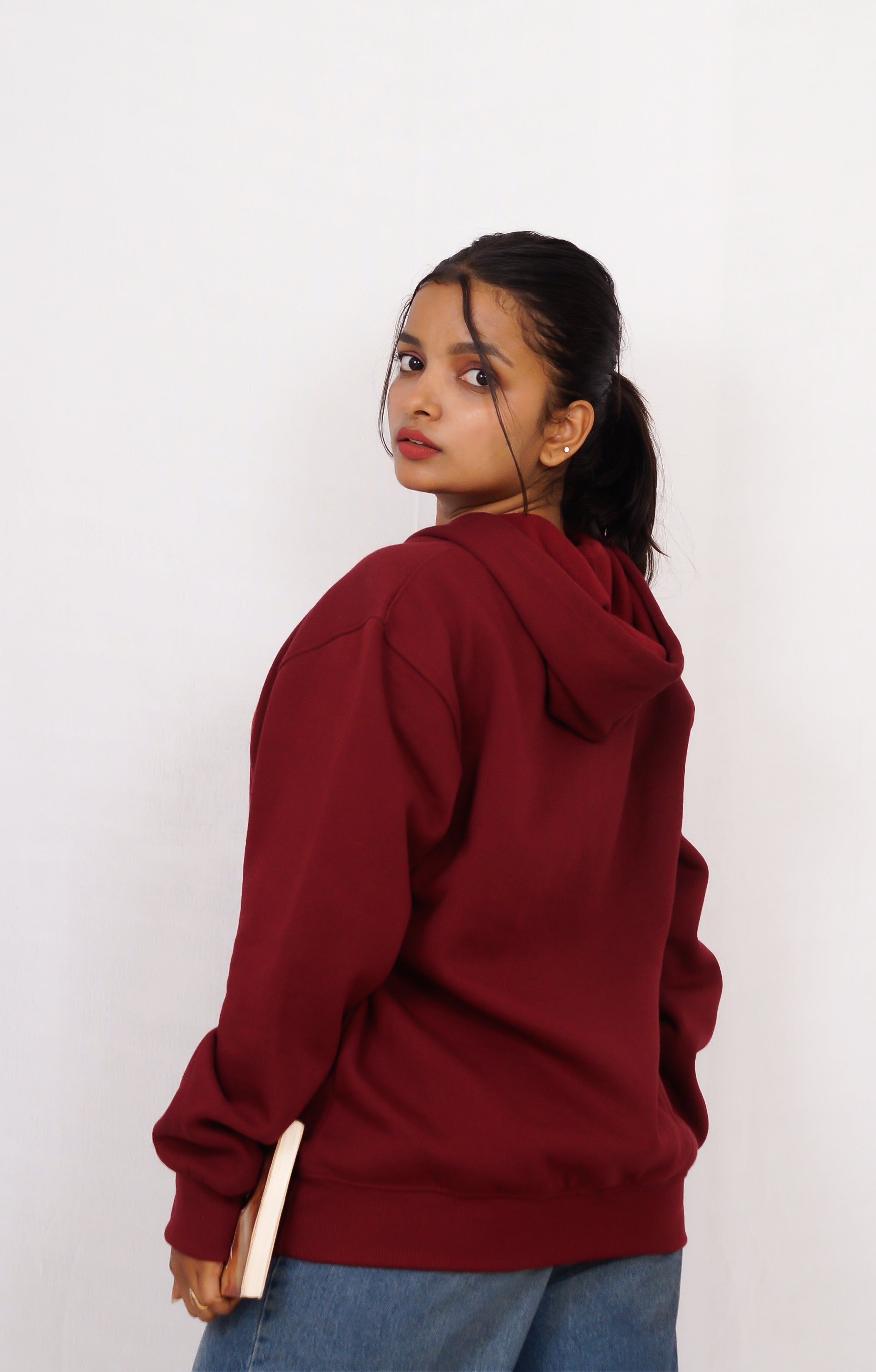 Person wearing a maroon hoodie against a white background