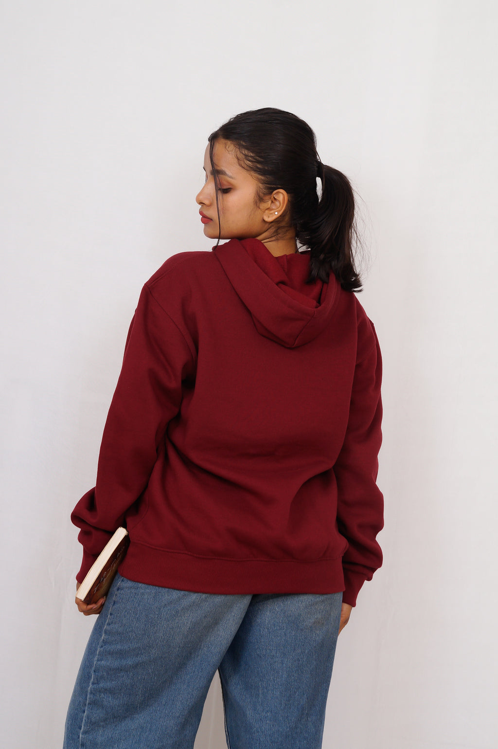 Person wearing a red hoodie and blue jeans against a white background