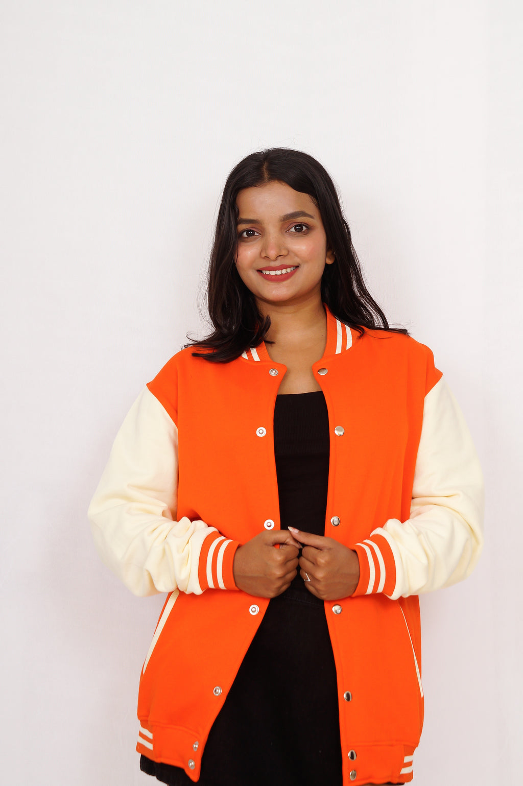 Person wearing an orange varsity jacket with white sleeves on a plain background