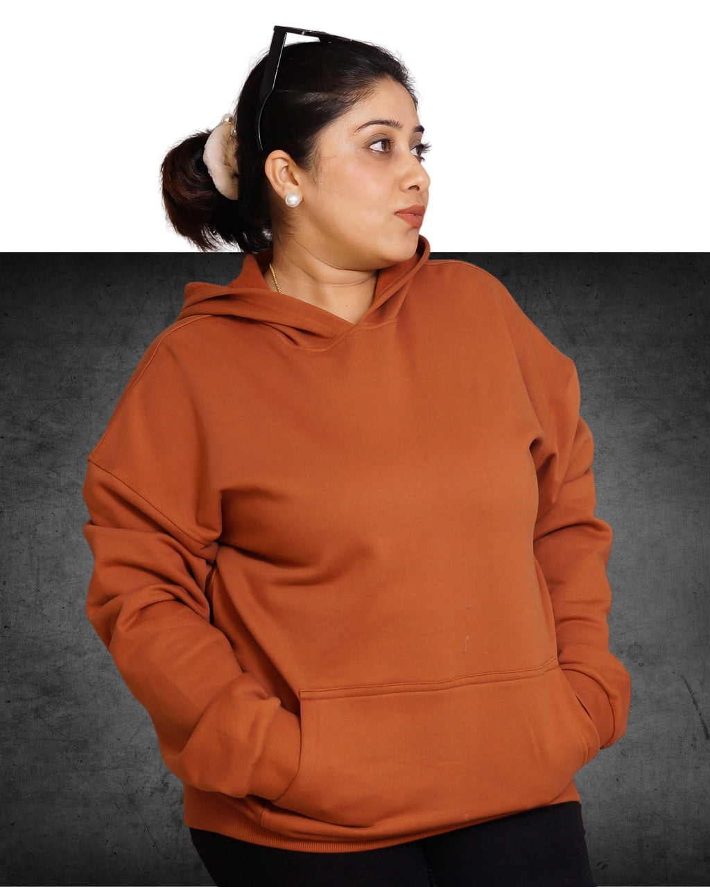 Person wearing a brown hoodie on a dark background