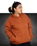 Person wearing a brown hoodie on a dark background