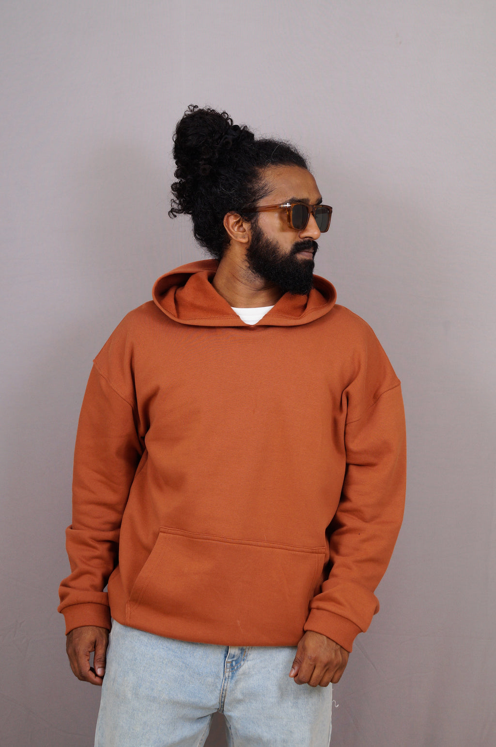 Man wearing an orange hoodie and sunglasses against a plain background