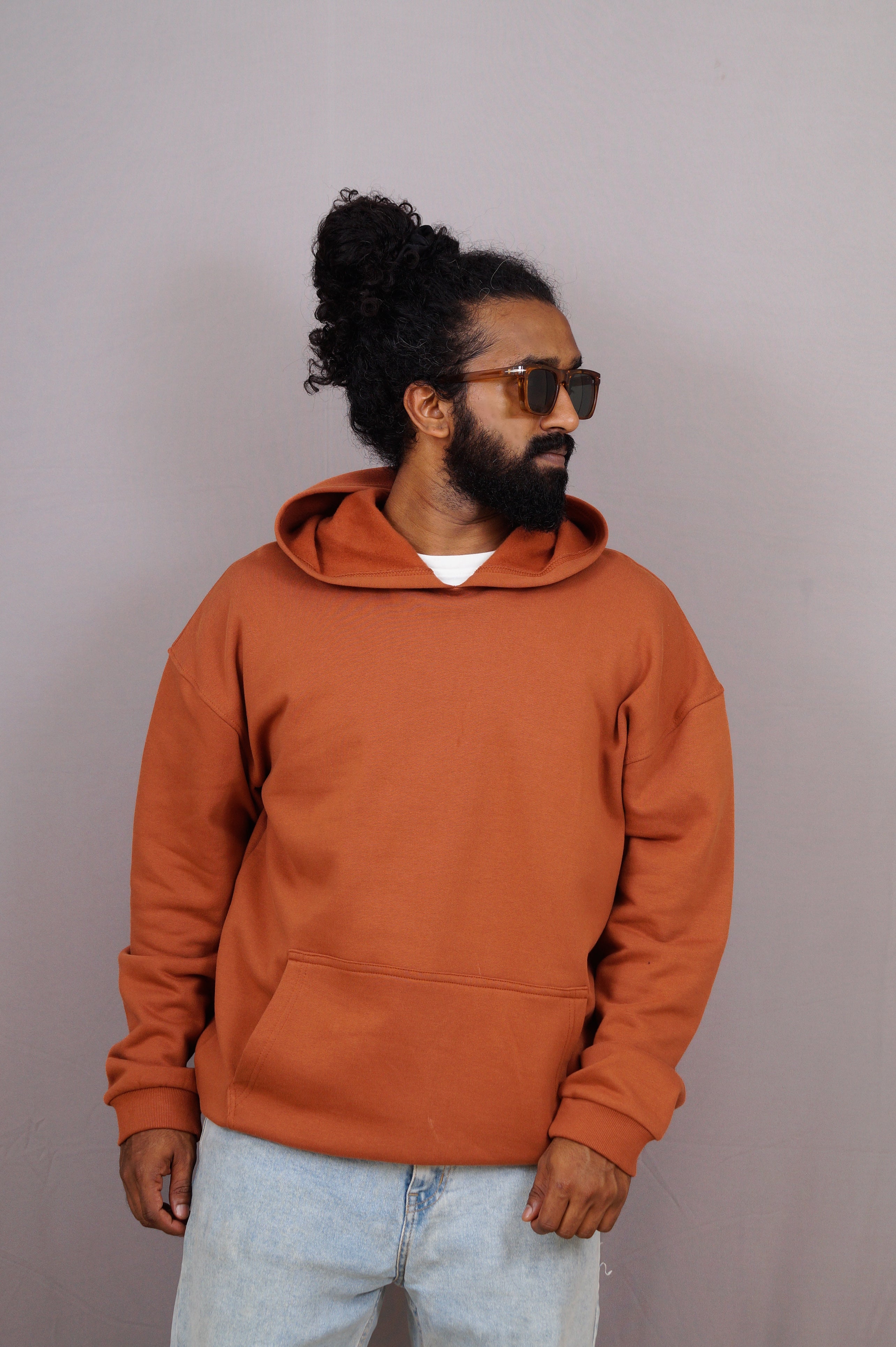 Man wearing an orange hoodie and sunglasses against a plain background