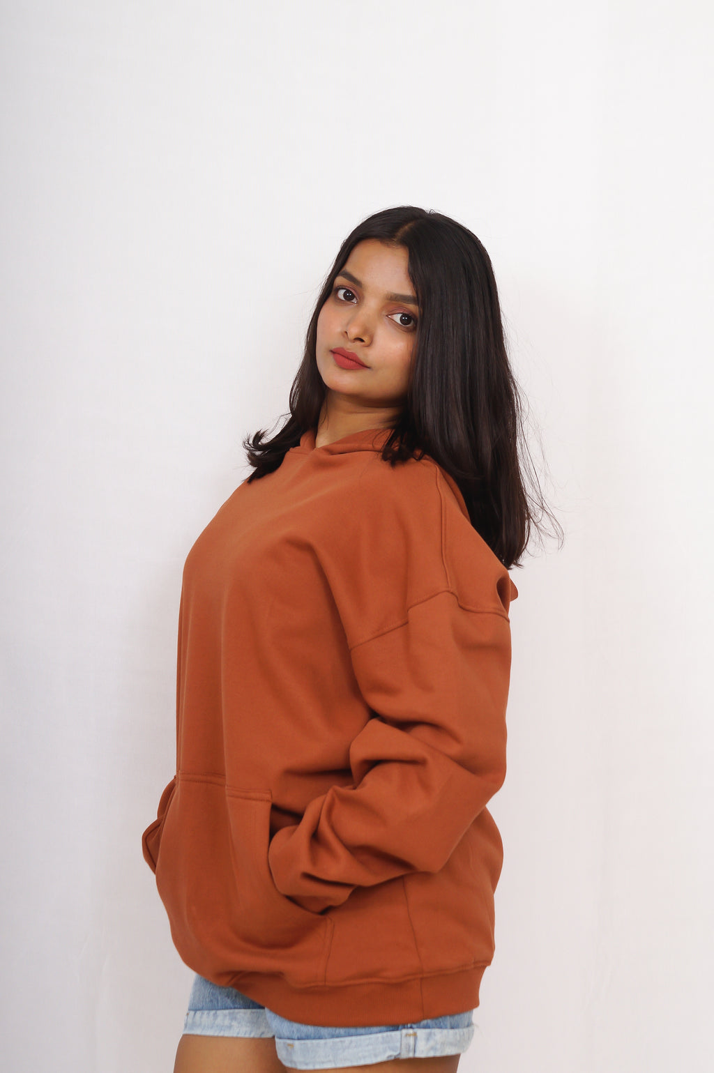 Person wearing a brown hoodie against a white background