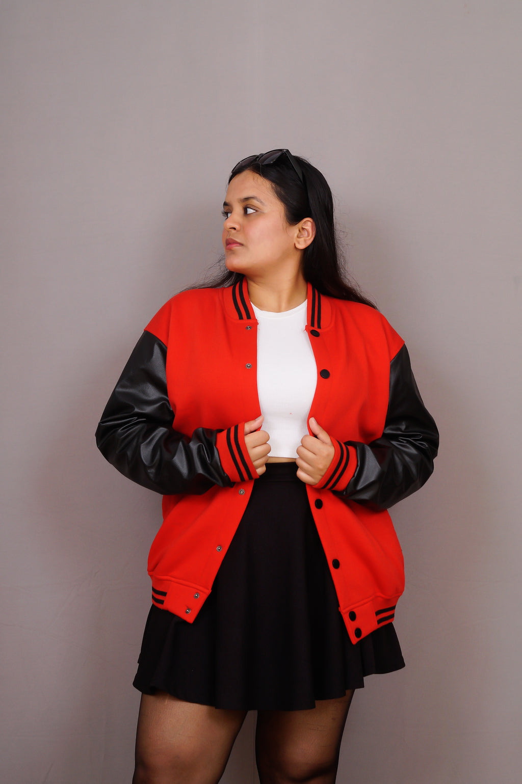 Person wearing a red and black varsity jacket on a plain background