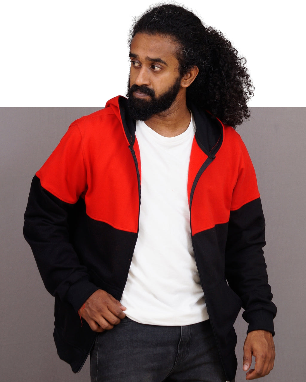 Man wearing a red and black jacket over a white shirt on a gray background