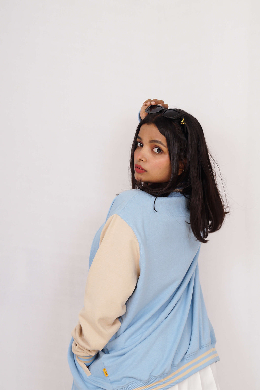 Person wearing a light blue cardigan over a beige long-sleeve shirt on a white background